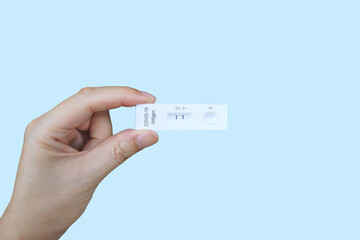 Hand holding Covid-19 Positive test result (Two Strips) with SARS CoV-2 Rapid Antigen Test Kit...