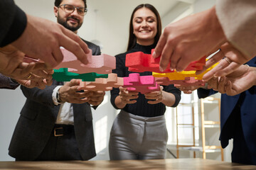 Group of business happy smiling people assembling big multicolor puzzle. Cooperation, teamwork,...