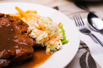 A plate of chicken chop set come with french fries and coleslaw