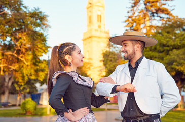 portrait Latin American man dressed as a huaso takes his cueca partner to dance by the arm