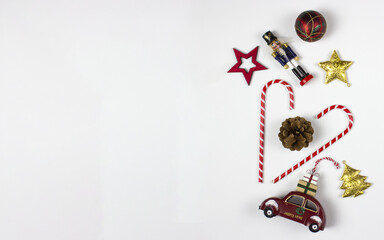 New Year flat lay with decorative objects: nutcracker, car, tree, candy, stars, gifts on white background. Free copy space for your text. Decorative object top view.