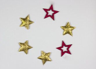 New Year flat lay with roundly placed golden and red stars on white background. Free copy space for your text. Decorative object top view.
