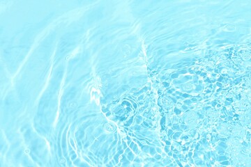 Blue water with ripples on the surface. Defocus blurred transparent blue colored clear calm water surface texture with splashes and bubbles. Water waves with shining pattern texture background.