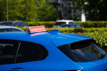 Swedish driver training sign on the roof of a blue car.