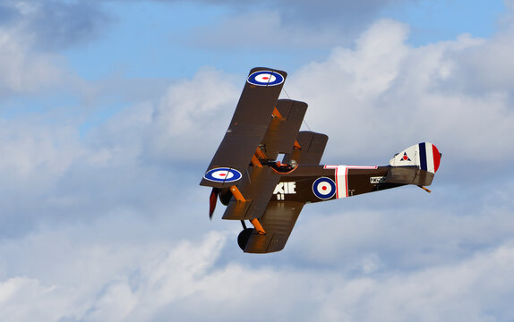 Vintage Sopwith Triplane in flight blue sky and clouds.