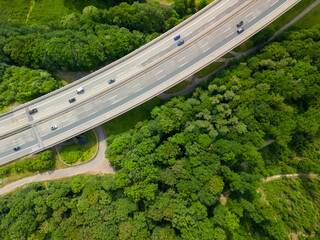 top down view of the highway bridge with the traffic going through the green forest