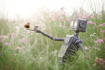Humanoid robot sits in a meadow among wild flowers and admires a butterfly. Robotic object experiences feelings and emotions. Concept of technology development in the form of artificial intelligence. - 626318721