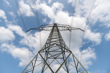 Low angle view of a transmission tower against the blue sky with white clouds 