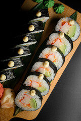 Closeup view of tasty sushi roll futomaki with avocado, crab meat and tobiko caviar on wooden serving board