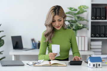 Asian businesswoman calculating bills, debts, insurance or loans Real Estate Home Residential Consult about mortgage loan offerings in the office.
