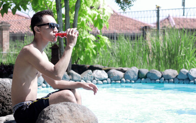 Fashion Portrait Of A Very Muscular Sexy Asian Man In Underwear At Swimming Pool with the green...