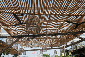 Many rattan lamps with electric fan hanging on bamboo ceiling