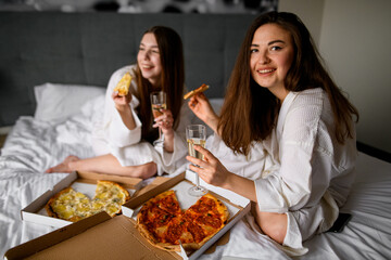 Beautiful women friends wearing bathrobes having fun at bachelorette party before wedding