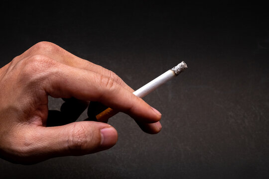The hand of a man, engrossed in the act of smoking, paints a poignant picture of self-inflicted harm to one's well-being.
