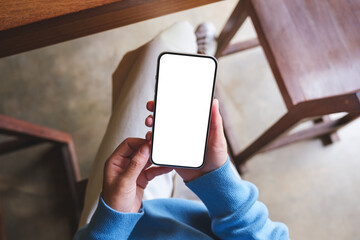 Top view mockup image of a woman using and holding mobile phone with blank screen