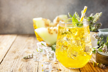 Fresh refreshing fruity summer drink, seasonal beverages. Melon lemonade in glasses with ice and mint on a wooden rustic table. Copy space.