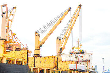 Fototapeta na wymiar Unloading operation of project cargo with port heavy lift cranes A crane on a large cargo ship docks loading a new diesel-electric locomotive. at Laem Chabang Port