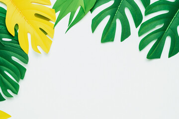 Fototapeta na wymiar Experience a minimal and exotic summer vibe with this creative layout of colorful tropical leaves on a white background, featuring ample copy space.