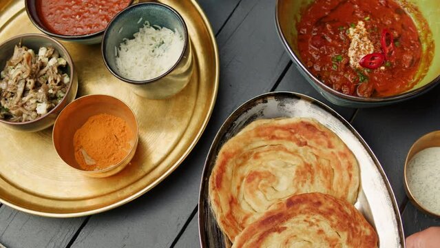 Assorted indian Sri Lankan food set on wooden background. Dishes and appetisers of indeed cuisine, rice, lentils, paneer, samosa, spices, masala. Bowls and plates with indian food top view chicken