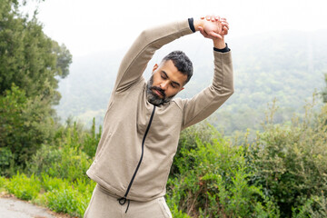 Ethnic man standing and stretching with tilted head against green meadow