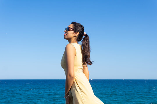 Indian female in dress enjoying summer vacation near sea