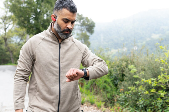 Man in sportswear looking at a digital watch outdoors