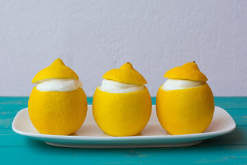 Three lemons stuffed with lemon ice cream on blue table and white background