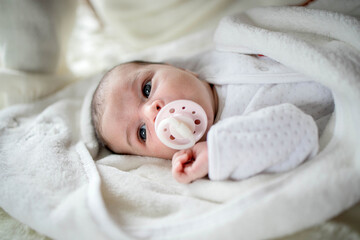 Newborn baby lying covered with white blanket.