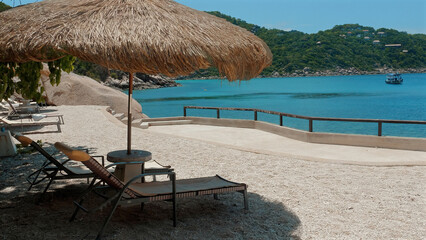 Enjoy the beautiful blue sea from a comfortable beach chair with straw umbrella. An idyllic spot...