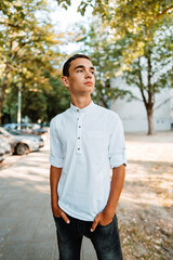 Handsome fashionable teenager standing on city street and posing.