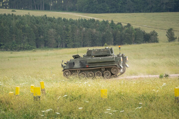 British army FV432 Bulldog APC hurtles down a country lane on a military exercise, Wiltshire UK