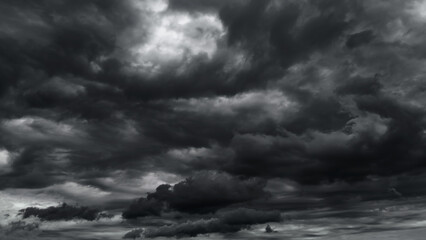 Fototapeta na wymiar dark dramatic sky with black stormy clouds before rain or snow as abstract background, extreme weather, the sun shines through the clouds, high contrast photo