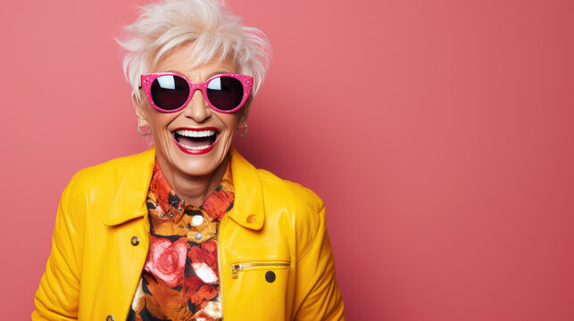 Happy and playful mature woman in stylish outfit on pink background.