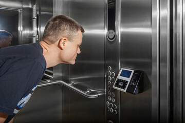 A man shows his face to a fingerprint access control terminal with a facial recognition function...