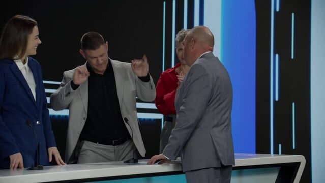 Funny charismatic host talking to the contestants during recording of a fictional morning family game show