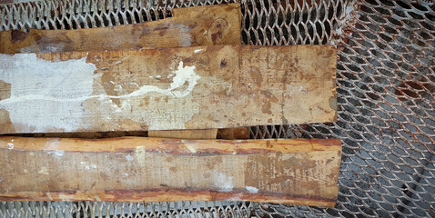 A construction site, on a metal lattice platform there are several boards made of pine wood, smeared with paint.