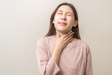 Sickness in inflaming asian young woman, girl use hand check self touch at sore throat, pain thyroid gland on neck or disease reflux, acid of suffer people on wall background. Medical and healthcare.