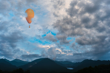 Fototapeta na wymiar Orange hot air balloon over the mountains