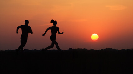 silhouette of a couple on a sunset background Running