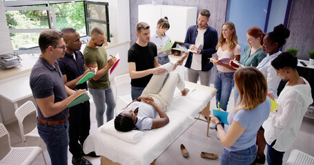 Male Instructor Teaching Massage Technique To Group