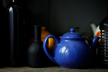 blue ceramic teapot among clay bottles, soft lighting