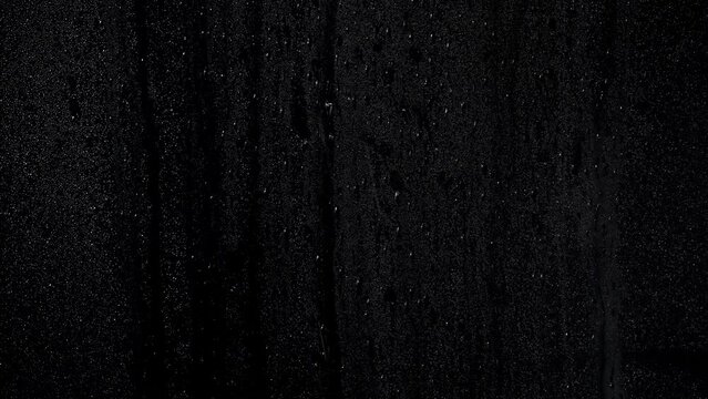 Drops on misty window with runny drops of water with a black background