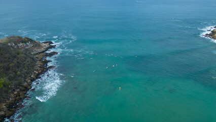 Above Carrizalillo beach at Puerto Escondido, Oaxaca, Mexico: aerial shot of surfers riding turquoise waves