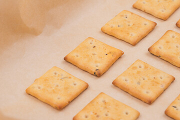 Spicy square crackers on parchment paper. Salty crackers closeup. Macro shot.