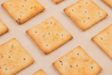 Spicy square crackers on parchment paper. Salty crackers closeup. Macro shot.