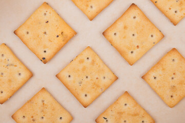 Spicy square crackers on parchment paper. Salty crackers closeup. Macro shot.