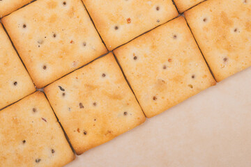 Spicy square crackers on parchment paper. Salty crackers closeup. Macro shot. Top view.