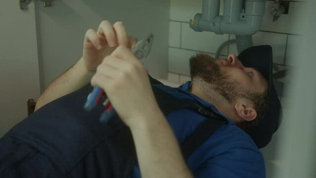 Expert Plumbing Technician Skillfully Repairs Sink Underneath in Residential Setting