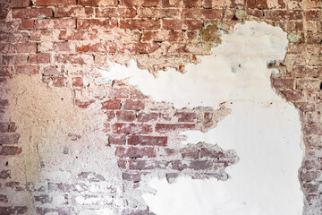 Old brick wall with peeling plaster, abstract background. Renovation of an old house.