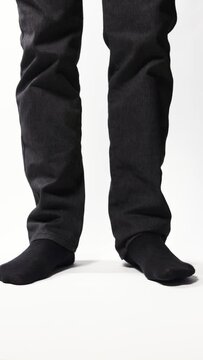 Legs of a man demonstrating black socks on a white background